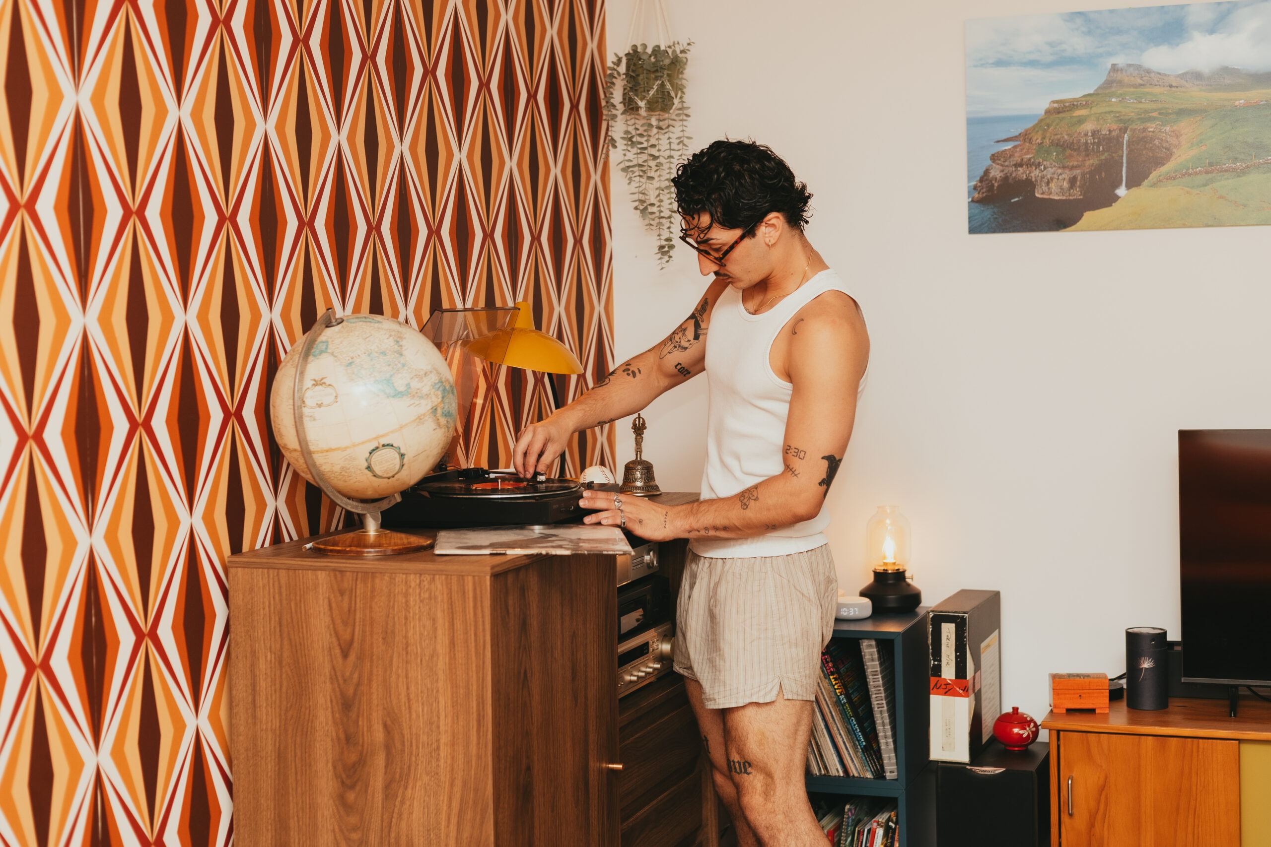 Théo choisissant un vinyle près d'un globe terrestre vintage, ambiance seventies