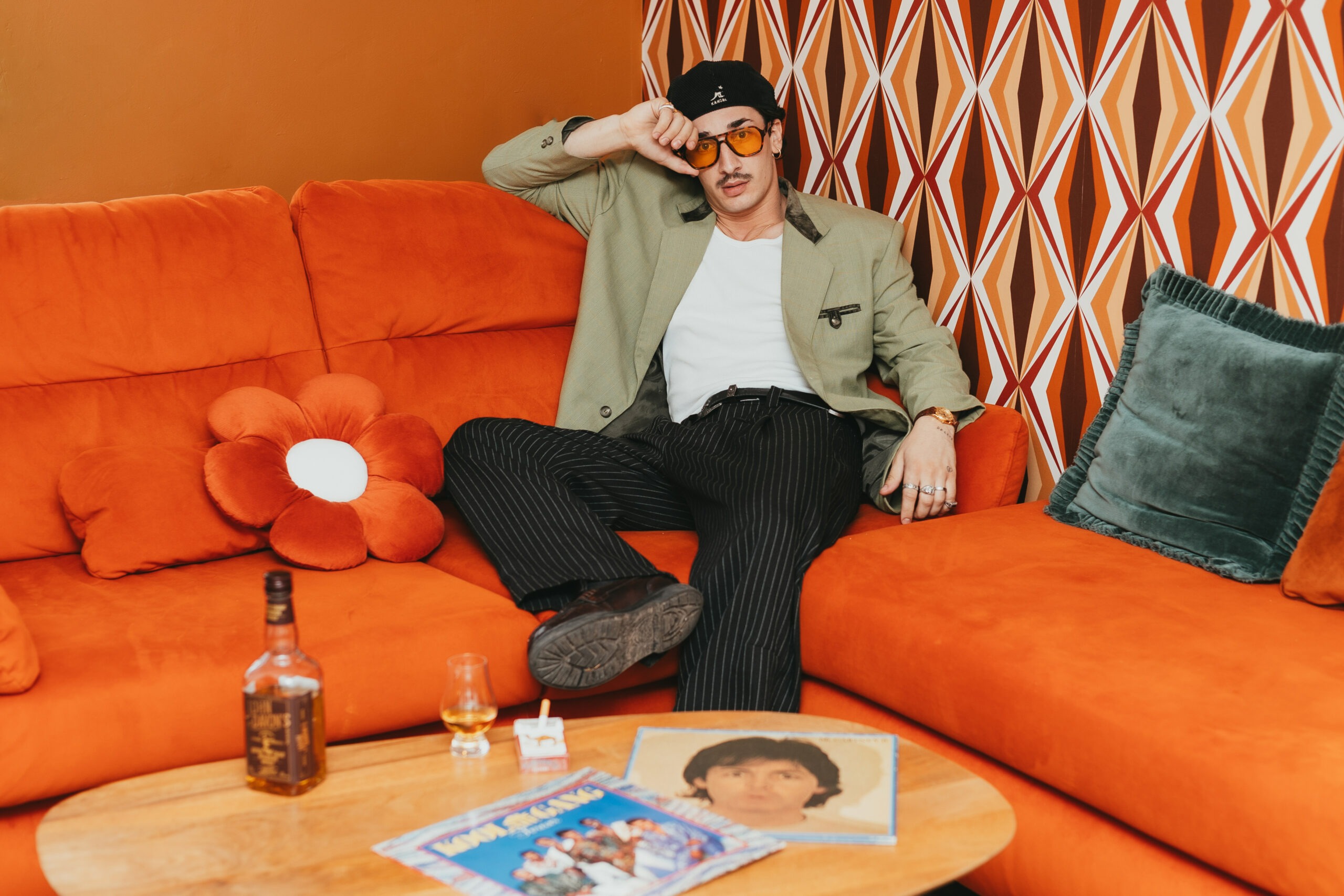 Théo sur un canapé en velours orange, cigarette et disques vinyles