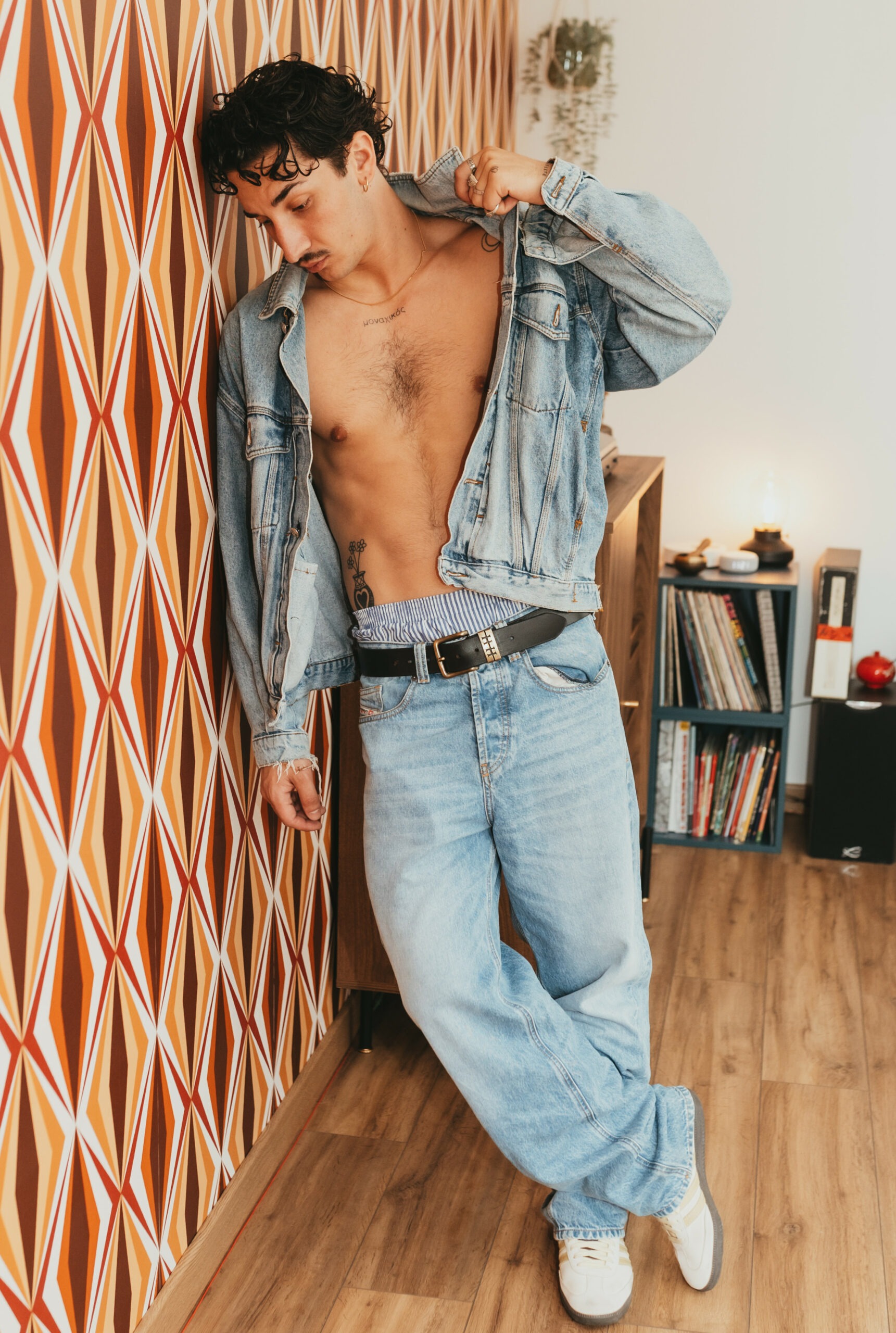 Théo en veste en jean devant une bibliothèque de vinyles, ambiance rétro