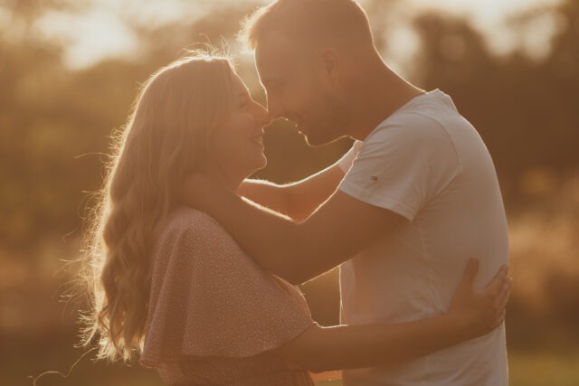 Couple enlacé, front contre front et sourire complice, en pleine nature