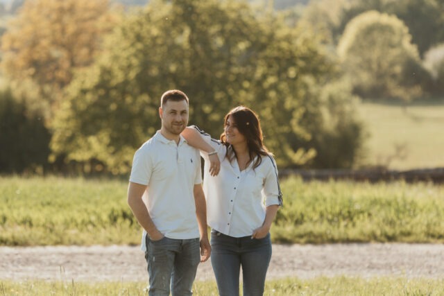 Couple complice posant dans un champ, elle appuyant la tête sur son épaule